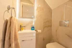 Matching marble walls in bathroom with LED-framed mirror